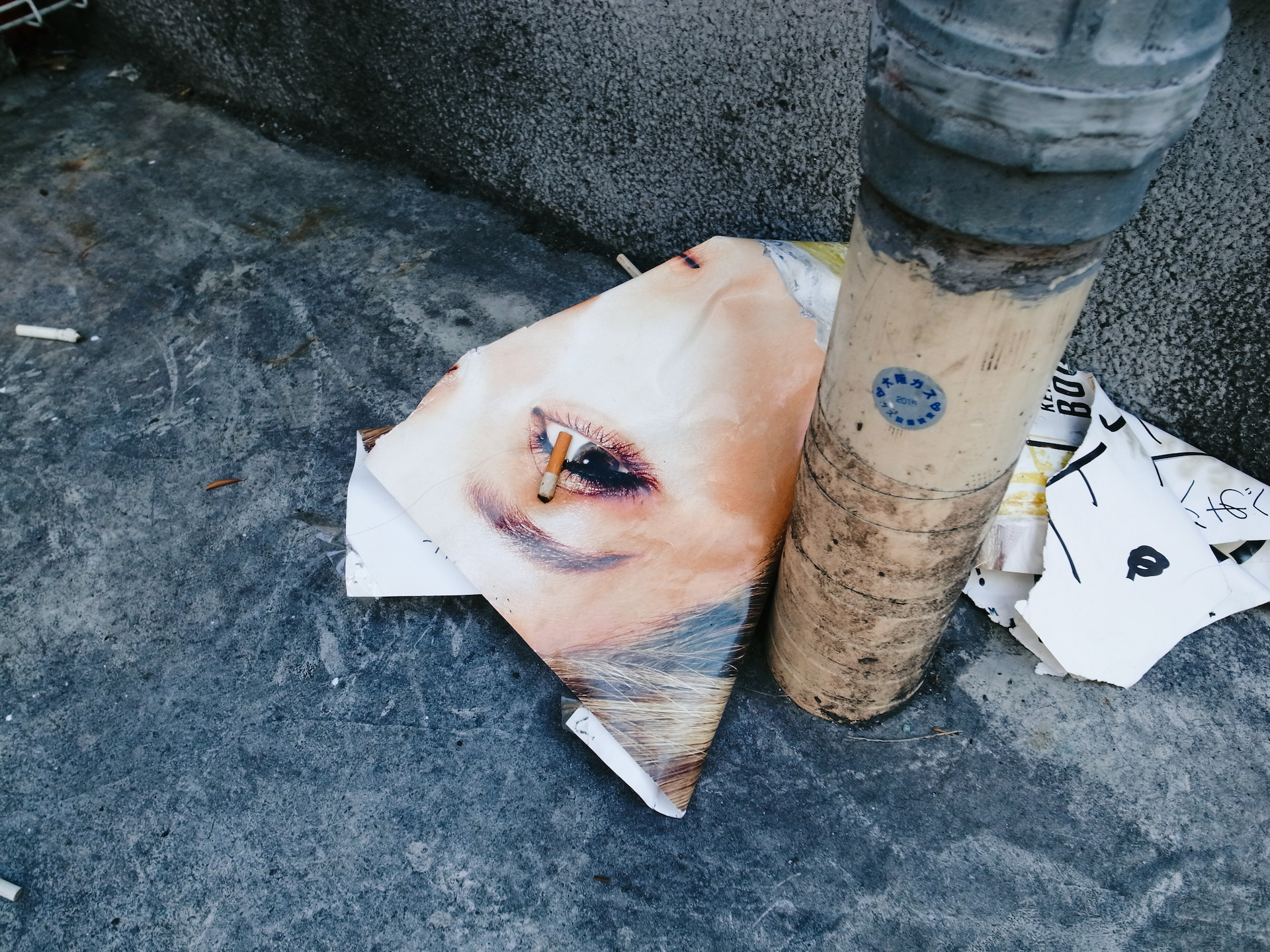 顔のポスターの上に落ちているタバコの吸い殻のRICOH GR DIGITAL IVの作例