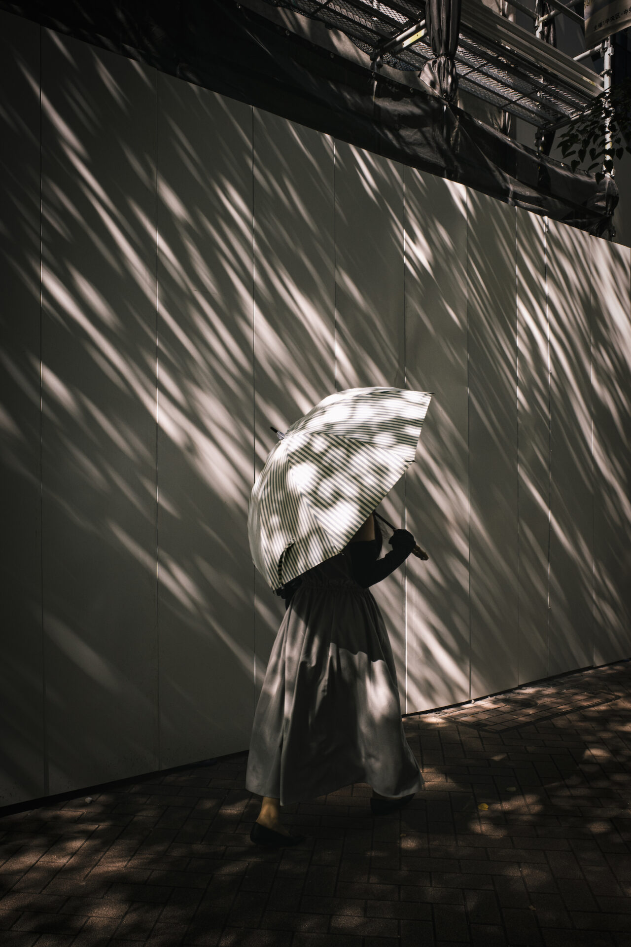 RICOH GR III Diary Editionで撮影したストライプの日傘をさしながら街を歩く女性の後ろ姿